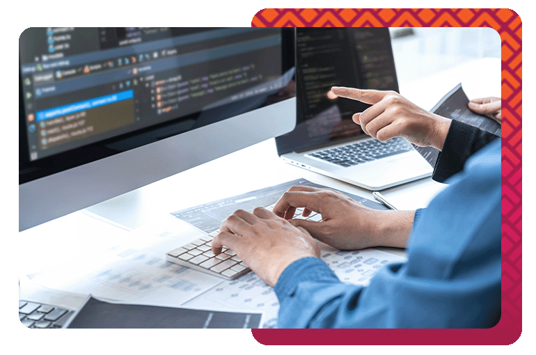 "Two professionals working on software development at a desk, with code displayed on computer screens, showcasing the technical expertise involved in 5280 PMO's software implementation services.