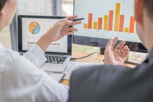 Optimization consultant reviewing performance metrics and data charts with a client to identify improvement opportunities.