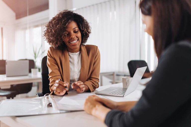 Smiling business consultant discussing optimization strategies with a client in a modern office setting.